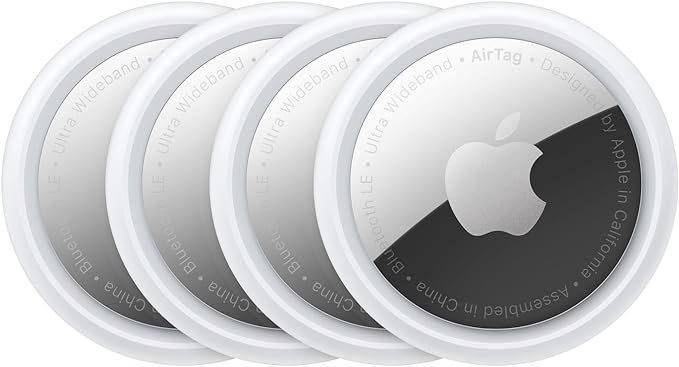 Four Apple AirTags arranged in a row, featuring the sleek circular design with silver and white finish—used for tracking personal items via Bluetooth.